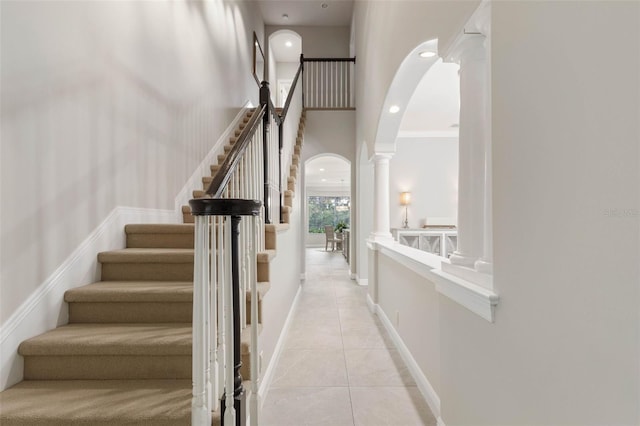 stairs featuring decorative columns, tile patterned floors, and crown molding