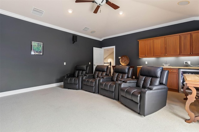 carpeted cinema room with wine cooler, ceiling fan, and ornamental molding