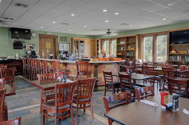 dining room with ceiling fan and a drop ceiling