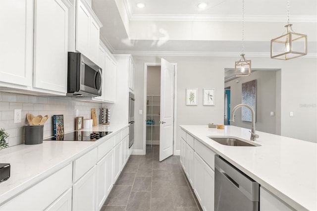 kitchen with stainless steel appliances, sink, dark tile patterned flooring, white cabinetry, and hanging light fixtures