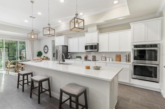 2214 Elegant Manor Cir, Edgewater, FL 32141 - kitchen featuring appliances with stainless steel finishes, tasteful backsplash, an island with sink, a breakfast bar area, and ornamental molding