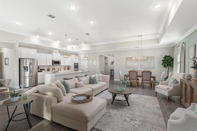 living room featuring a notable chandelier, a raised ceiling, and ornamental molding