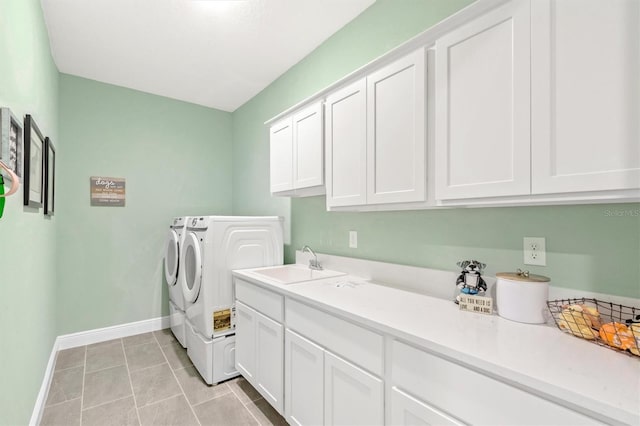 clothes washing area with washer and clothes dryer, cabinets, and sink