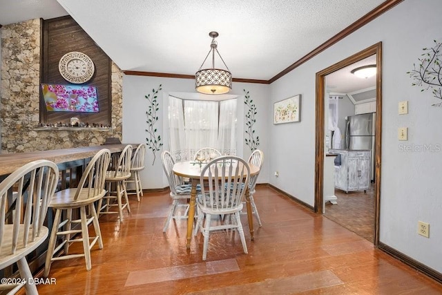 dining space featuring a textured ceiling, wood finished floors, and crown molding