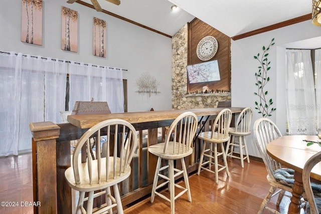 dining area featuring wood finished floors, ornamental molding, a ceiling fan, and vaulted ceiling