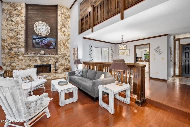 living room with crown molding, baseboards, a fireplace, a high ceiling, and wood finished floors