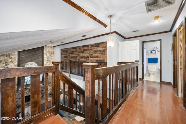 hall with an upstairs landing, visible vents, and wood finished floors