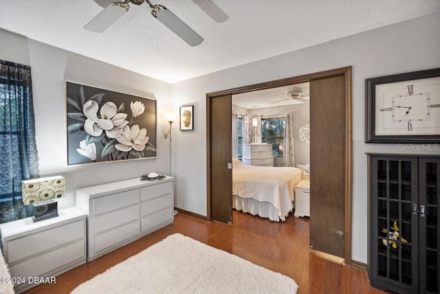 bedroom featuring a ceiling fan, wood finished floors, baseboards, and a textured ceiling