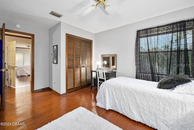 bedroom featuring visible vents, multiple windows, a closet, and wood finished floors