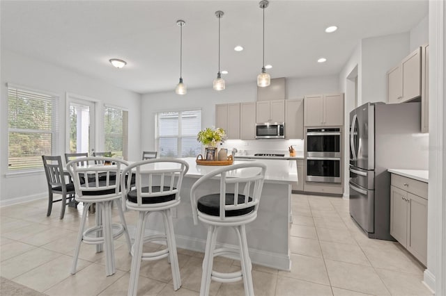 kitchen with gray cabinetry, a center island, decorative light fixtures, light tile patterned floors, and appliances with stainless steel finishes