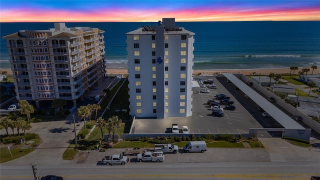 aerial view at dusk with a water view and a view of the beach