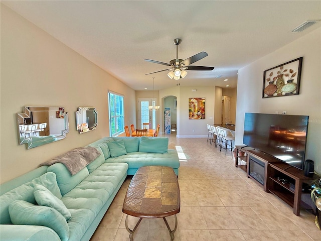 tiled living room featuring ceiling fan with notable chandelier