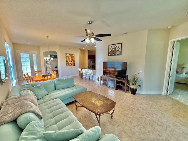 tiled living room with ceiling fan with notable chandelier