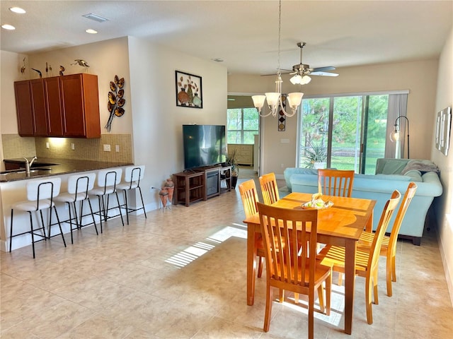 tiled dining room with ceiling fan with notable chandelier, a healthy amount of sunlight, and sink