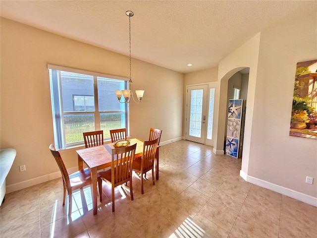 dining room with light tile patterned floors, a textured ceiling, and a notable chandelier