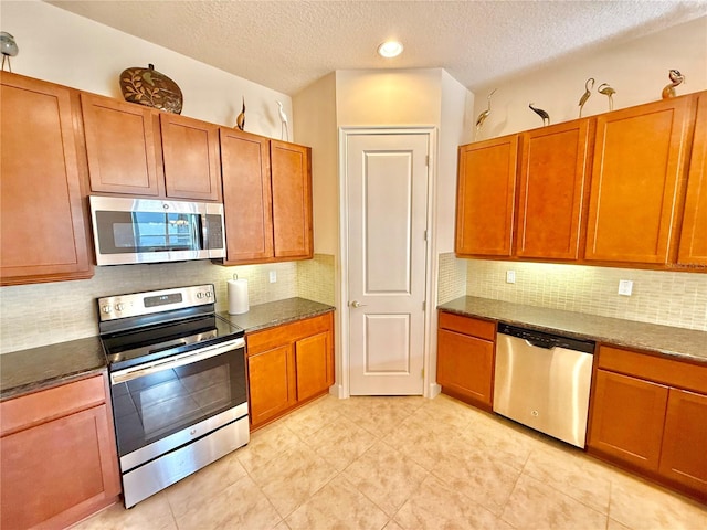 kitchen featuring a textured ceiling, backsplash, and stainless steel appliances