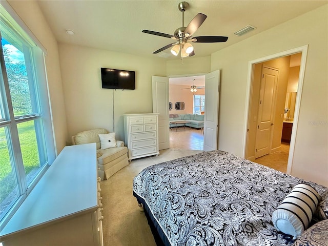 bedroom with multiple windows, ceiling fan, and light colored carpet