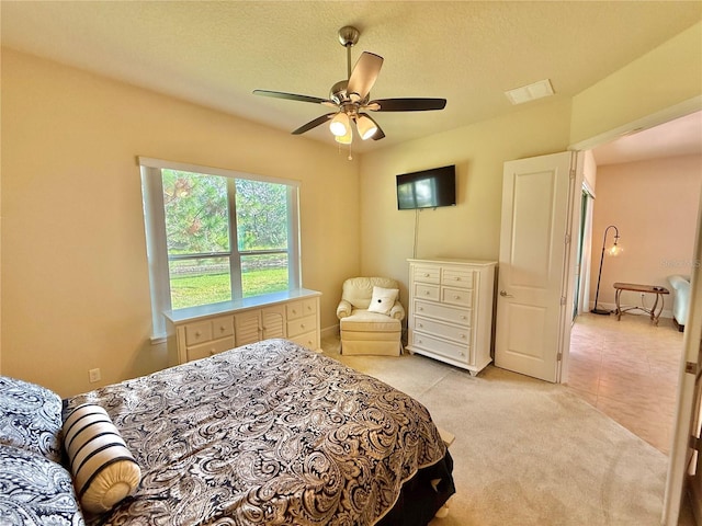 carpeted bedroom with ceiling fan and a textured ceiling