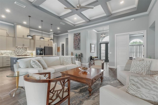 living room with ornamental molding, coffered ceiling, ceiling fan with notable chandelier, beam ceiling, and hardwood / wood-style floors