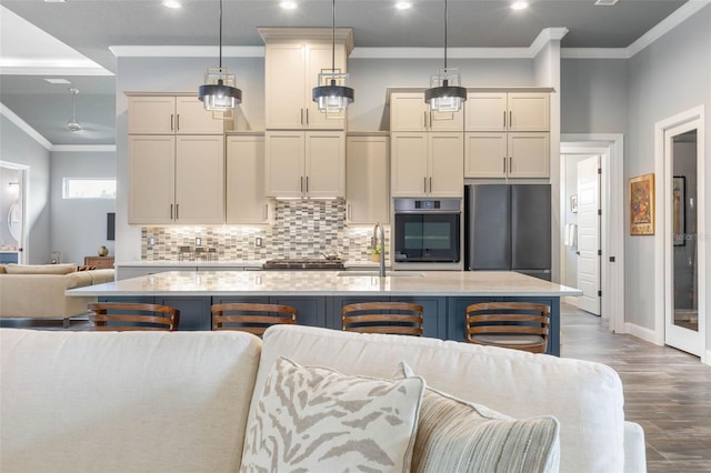 kitchen with a center island with sink, decorative light fixtures, a kitchen bar, wood-type flooring, and stainless steel appliances