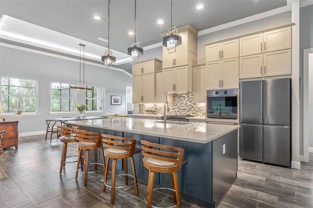 kitchen featuring pendant lighting, sink, an island with sink, appliances with stainless steel finishes, and light stone counters