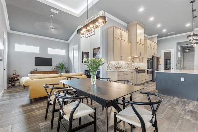 dining area featuring hardwood / wood-style flooring, sink, a notable chandelier, and ornamental molding