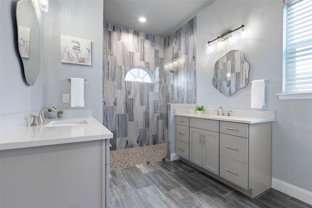 bathroom with a tile shower and vanity