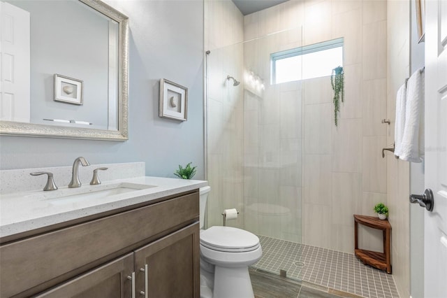 bathroom featuring tiled shower, vanity, and toilet