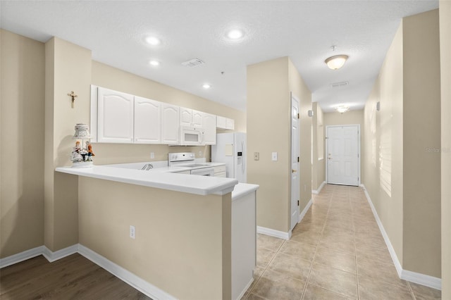 kitchen featuring kitchen peninsula, a textured ceiling, white appliances, and white cabinetry