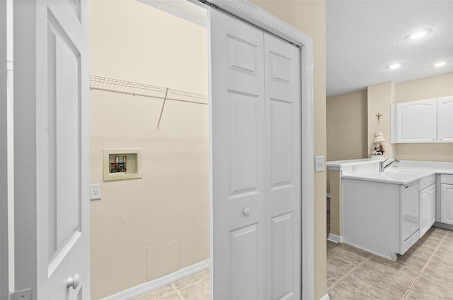 laundry area featuring washer hookup, cabinets, light tile patterned floors, and sink