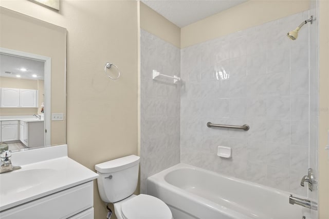 full bathroom with a textured ceiling, vanity, toilet, and tiled shower / bath