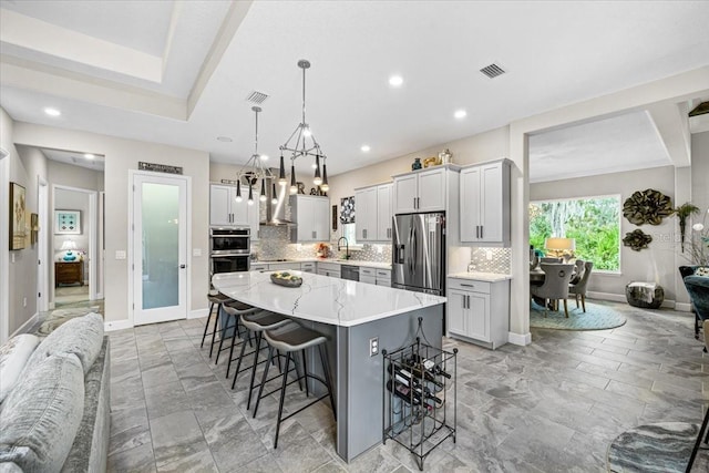 kitchen featuring a center island, stainless steel appliances, hanging light fixtures, and tasteful backsplash