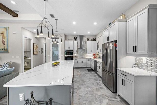 kitchen with decorative backsplash, a spacious island, wall chimney range hood, and stainless steel appliances