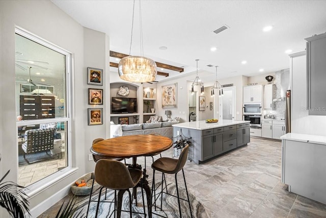 kitchen with gray cabinetry, a center island, backsplash, decorative light fixtures, and white cabinets