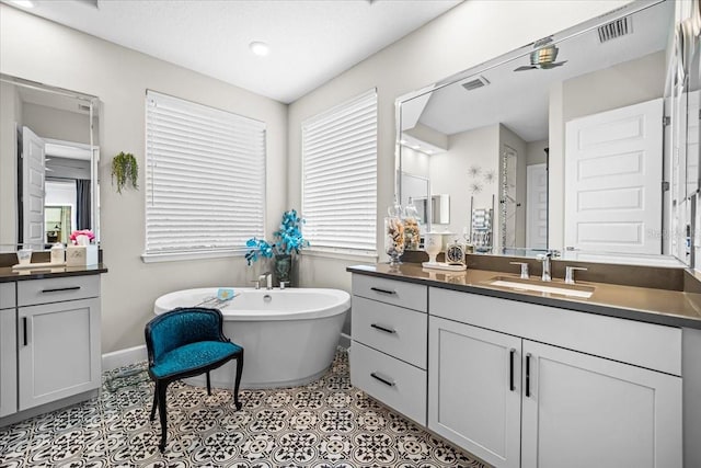 bathroom with tile patterned flooring, a washtub, and vanity