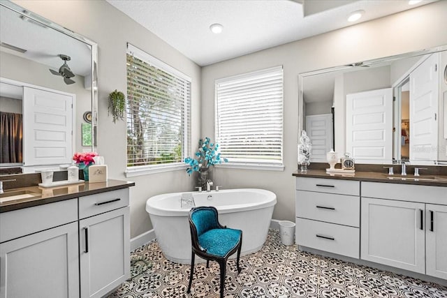 bathroom featuring a tub, tile patterned flooring, vanity, and a textured ceiling