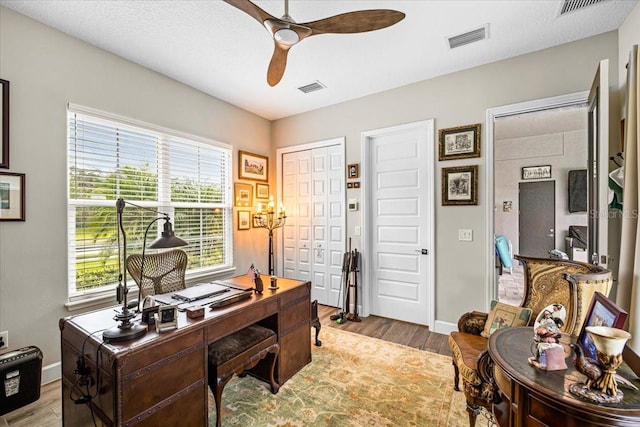 office with a textured ceiling, light hardwood / wood-style floors, and ceiling fan