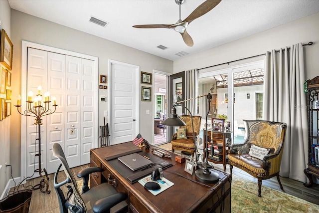 home office featuring ceiling fan with notable chandelier and hardwood / wood-style flooring