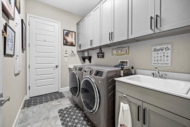 clothes washing area with washer and dryer, cabinets, and sink