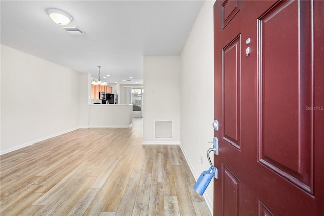 foyer entrance featuring a chandelier and light hardwood / wood-style floors