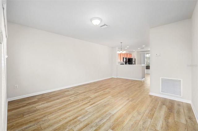 unfurnished living room with light hardwood / wood-style floors and an inviting chandelier