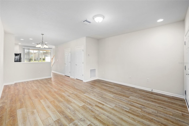 unfurnished living room with light wood-type flooring and a chandelier