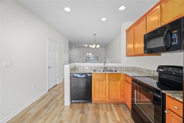 kitchen with light stone counters, sink, black appliances, and light wood-type flooring