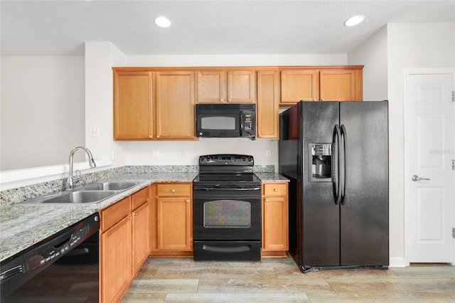 kitchen featuring black appliances, light stone countertops, sink, and light hardwood / wood-style flooring