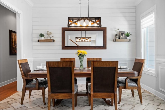 dining room with wood walls and ornamental molding