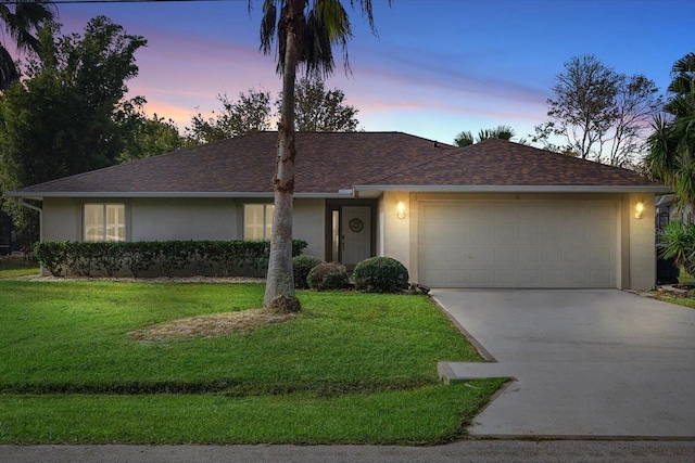 single story home with a garage and a lawn