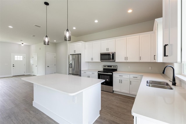 kitchen with white cabinetry, a center island, sink, stainless steel appliances, and hardwood / wood-style flooring