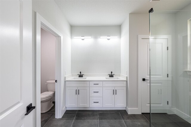 bathroom featuring tile patterned flooring, vanity, a textured ceiling, and toilet