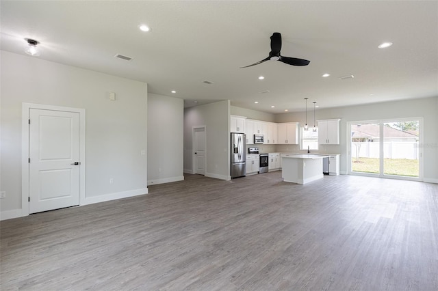 unfurnished living room featuring ceiling fan, light wood-type flooring, and sink