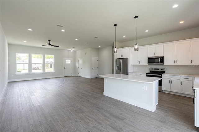 kitchen with white cabinets, hardwood / wood-style floors, a center island, and stainless steel appliances